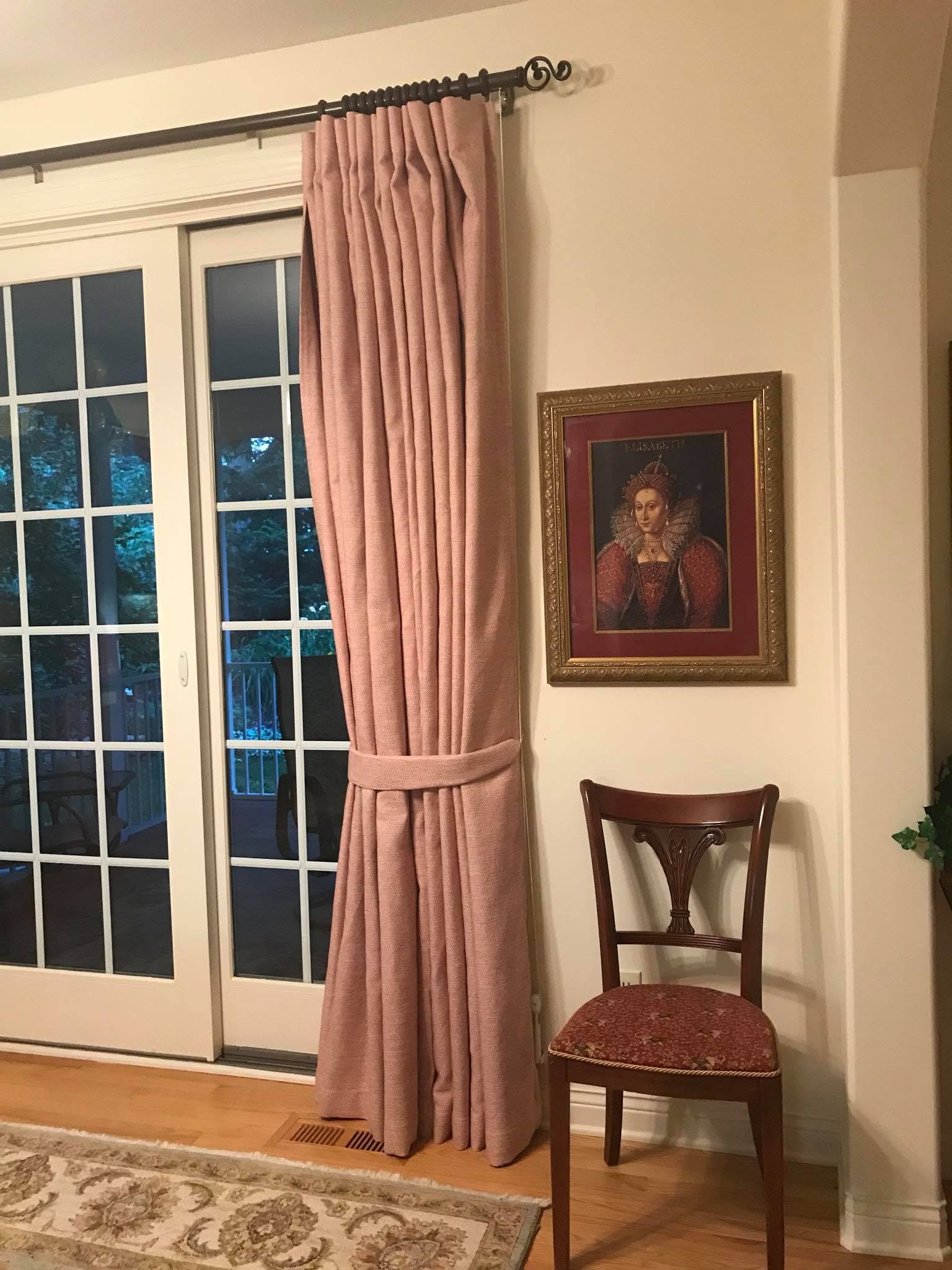 Rose pinch-pleat drapery with a fabric tieback beside a French door
