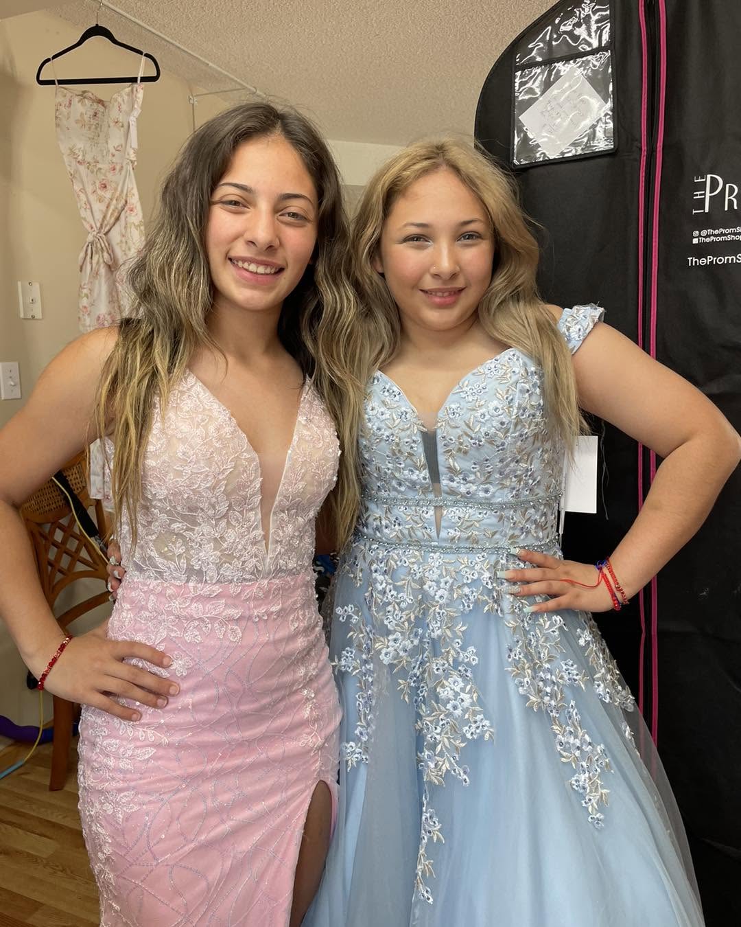Two young women wearing altered prom dresses in pink and powder blue